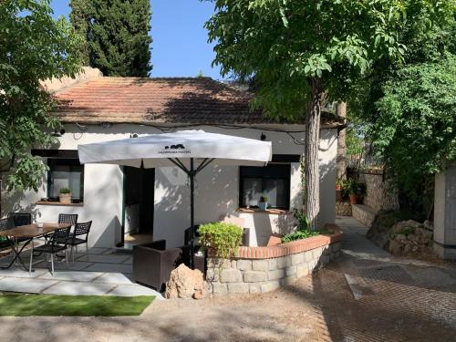een wit huis met een tafel en een paraplu bij Casa Rural 3 en un fantástico legado in Alfacar