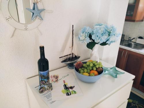 a table with a bottle of wine and a bowl of fruit at Apartmán BRAĆKI CVIJET in Sutivan