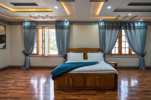 een slaapkamer met een houten bed met blauwe lakens en ramen bij Dirleh Hotel in Skardu