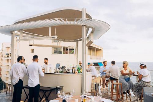 Un groupe de personnes autour d'un bar dans l'établissement Hôtel & Spa Belle Plage, à Cannes