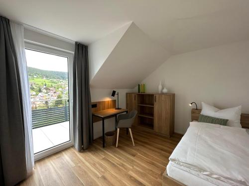 Schlafzimmer mit einem Bett und einem Schreibtisch mit einem Fenster in der Unterkunft Ferienhaus Waldschatz Baiersbronn in Baiersbronn