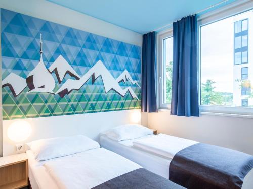 a bedroom with two beds and a mural of mountains at B&B Hotel Rosenheim in Rosenheim