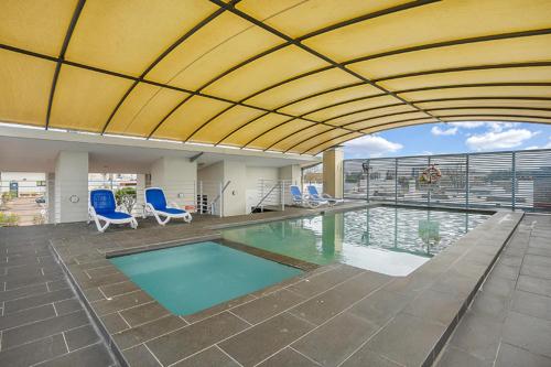 une piscine avec des chaises bleues et un bâtiment dans l'établissement Contemporary Apartment, à Sydney