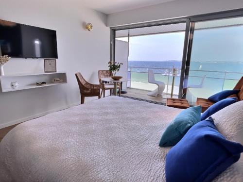 a bedroom with a large bed and a view of the ocean at Le Souffle Marin CONCARNEAU - VUE MER panoramique DIRECT sur la PLAGE des Sables Blancs FIBRE Parking PRIVÉ Secure PANORAMIC SEE VIEW direct ON BEACH in Concarneau
