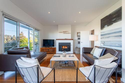a living room with a couch and chairs and a fireplace at Nikabel Beach House I Private Properties in Dunsborough