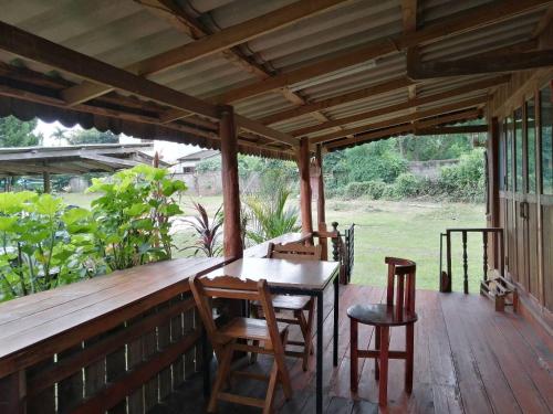een houten veranda met een tafel en stoelen erop bij Baanpak Chomdoi in Nan