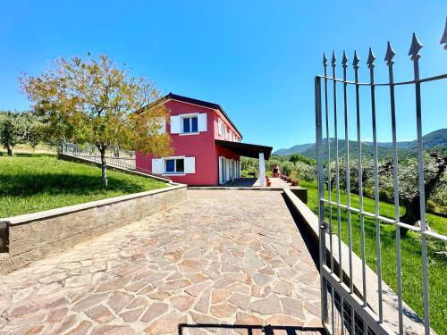 a fence in front of a red house at Villa San Bartolo in San Vincenzo