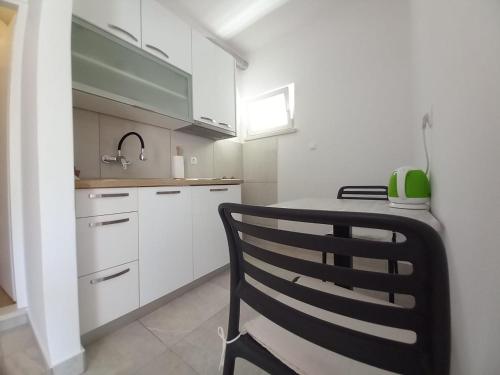 una cocina con armarios blancos y una silla negra en Accommodation Drasko en Korčula