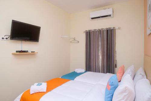 a bedroom with a white bed with a flat screen tv at Sans Hotel City Park Medoho Semarang in Alastuwo