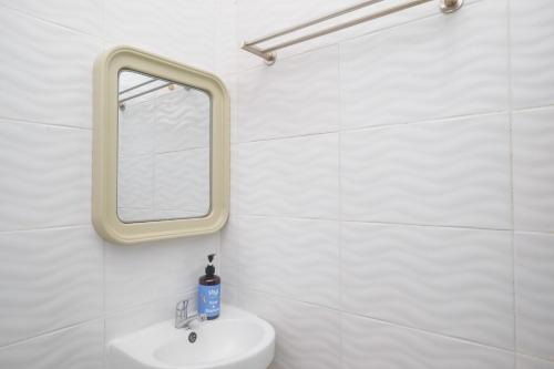 ein weißes Badezimmer mit einem Spiegel und einem Waschbecken in der Unterkunft Sans Hotel City Park Medoho Semarang in Alastuwo