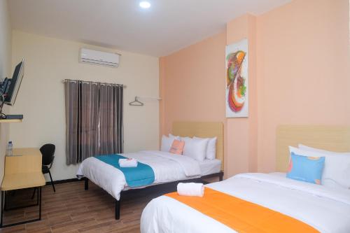 a hotel room with two beds and a desk at Sans Hotel City Park Medoho Semarang in Alastuwo
