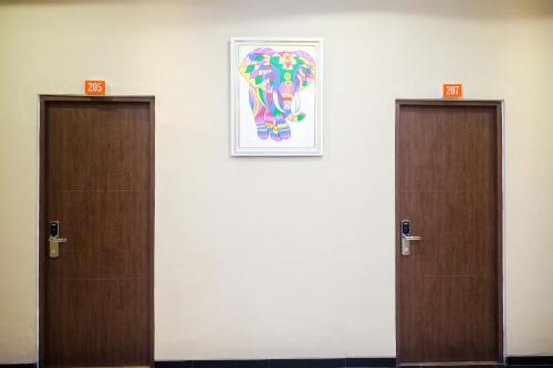 two doors in a room with a picture on the wall at Sans Hotel City Park Medoho Semarang in Alastuwo