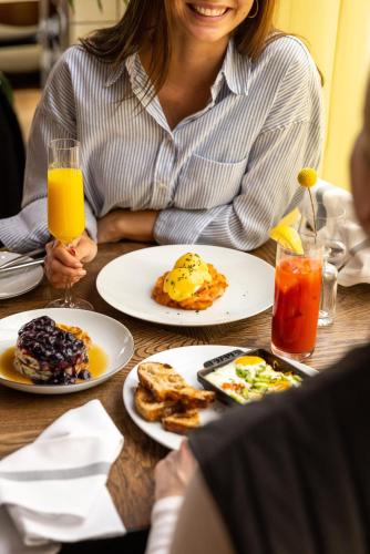 a woman sitting at a table with plates of breakfast food at Kimpton De Witt Amsterdam by IHG in Amsterdam