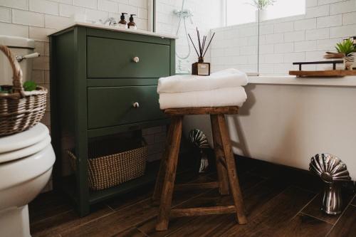 a bathroom with a green cabinet and a stool with towels at Swallow Cottage, Bakewell in Bakewell