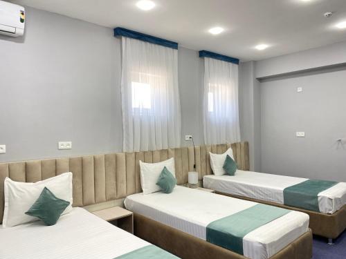 a hotel room with two beds and a window at Aperol Hotel in Tashkent