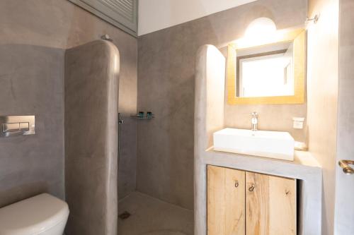 een badkamer met een wastafel, een toilet en een spiegel bij Mosha Pension in Kamarai