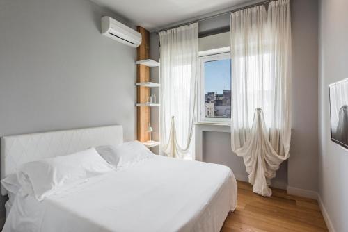 a white bedroom with a white bed and a window at Ferrini Home - Suites in Catania