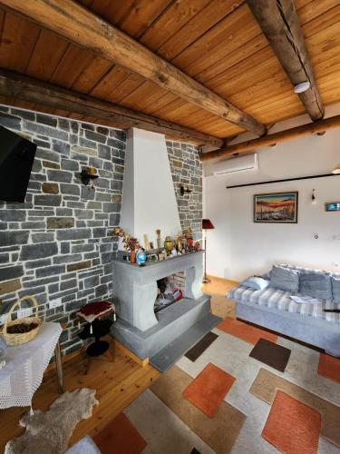 Una sala de estar con chimenea de piedra y un sofá. en Villa Shuaipaj, en Gjirokastra