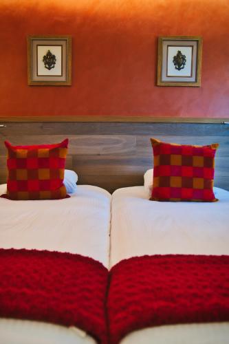 two beds with red pillows in a room at Château des Avenieres in Cruseilles