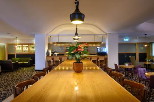 a large wooden table with a vase of flowers on it at Prima Park Hotel Jerusalem in Jerusalem