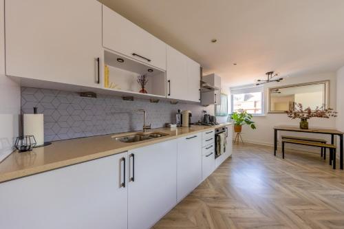 a kitchen with white cabinets and a wooden floor at Central Shoreditch Flat By Box Park & Spitalfields Market in London