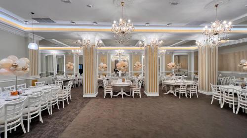 a banquet hall with white tables and chairs and chandeliers at Casa Micle in Craiova