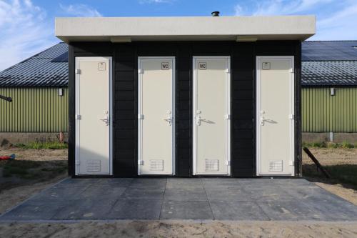 a group of four white doors in a building at De Zuidvliet Glamping Deluxe 1 in Wolphaartsdijk