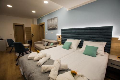 una camera da letto con un grande letto con lenzuola bianche e cuscini verdi di Klečka vila B&B rooms a Ogulin
