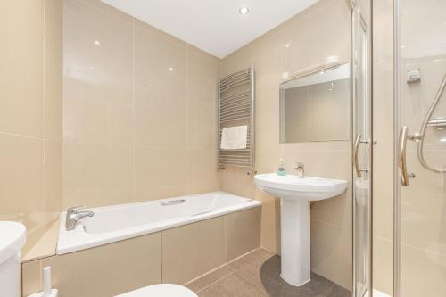 a bathroom with a tub and a sink and a toilet at Bay View Apartments in Port Erin