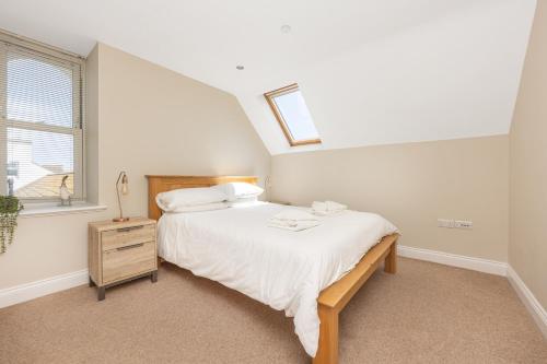 a white bedroom with a bed and a window at Bay View Apartments in Port Erin