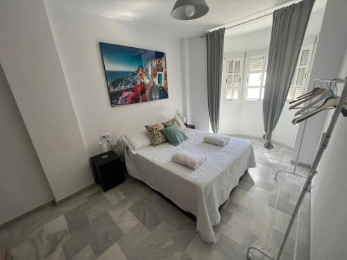 1 dormitorio con 1 cama y una pintura en la pared en Piso en Calzada duquesa Isabel, en Sanlúcar de Barrameda