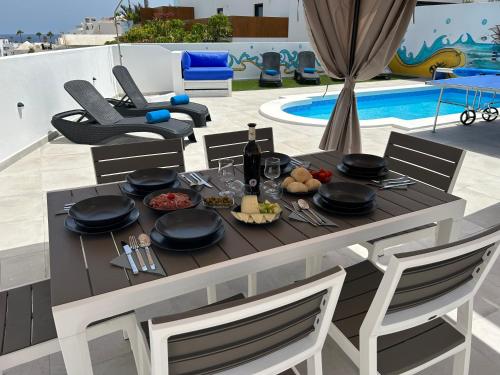 un tavolo con cibo e vino accanto a una piscina di Casa Vedas - 3 bedroom villa with private pool a Puerto del Carmen