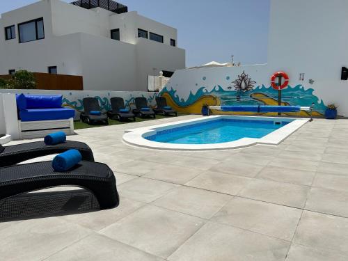 una piscina con sedie e un murale su un edificio di Casa Vedas - 3 bedroom villa with private pool a Puerto del Carmen