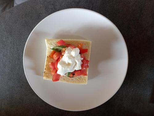 a white plate with a piece of bread with fruit and whipped cream at LA TANA DELLA VOLPETTA - Bed & Breakfast in Stella