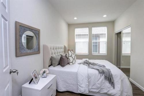 a bedroom with a white bed and a mirror at San Jose Shark House - Unit 2 in San Jose