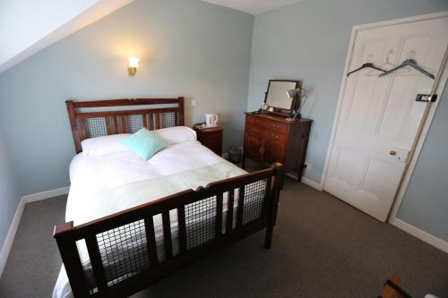a bedroom with a bed and a dresser and a door at Rolling Wave Guesthouse in Bundoran
