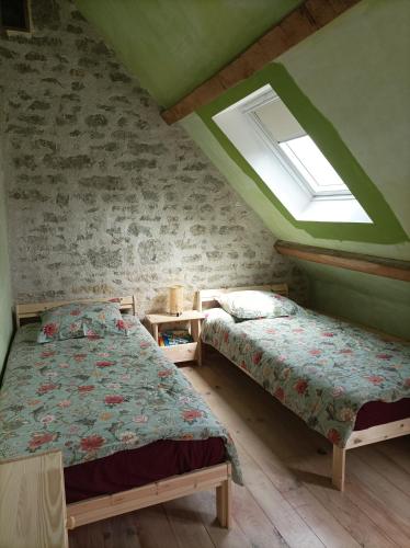 deux lits dans une chambre avec une fenêtre dans l'établissement Longère avec piscine, à Couffy