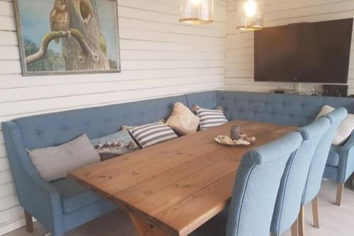 einen Holztisch mit zwei blauen Stühlen und einem TV in der Unterkunft Charming beach house in Moss