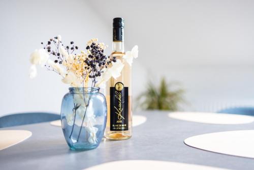 a bottle of wine sitting next to a vase with flowers at Design-Ferienwohnung in Kelberg am Nürburgring: Platz für 6, Küche, WiFi, Netflix in Kelberg