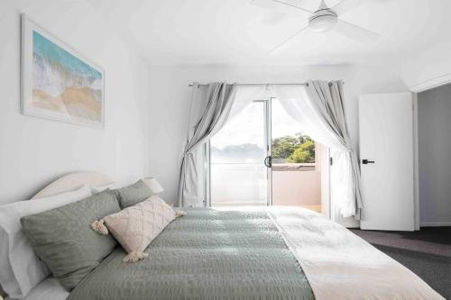 a bedroom with a bed and a large window at Stylish family friendly oasis - Lette @ Corlette in Corlette