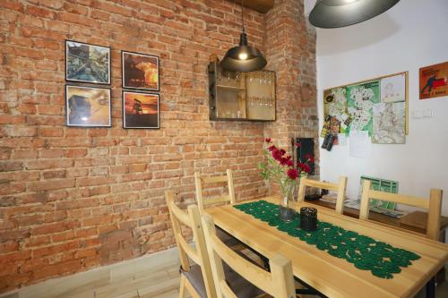 a dining room with a brick wall and a wooden table at Apartament Gwarek in Wałbrzych