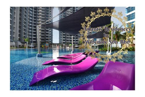una fila di sedie viola in piscina di Atlantis Residence - Widenote Sdn Bhd a Malacca