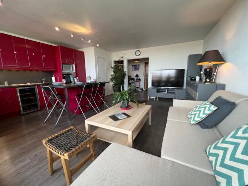 un salon avec un canapé et une cuisine avec des armoires rouges dans l'établissement Above Paris Eiffel Tower view Balcony, à Paris