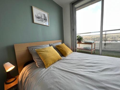 Cette chambre dispose d'un lit avec des oreillers jaunes et d'une fenêtre. dans l'établissement Above Paris Eiffel Tower view Balcony, à Paris
