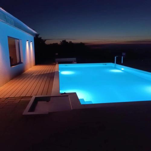 a swimming pool with blue lighting on a house at night at Nagypince Borhotel Wine and Spa in Böhönye