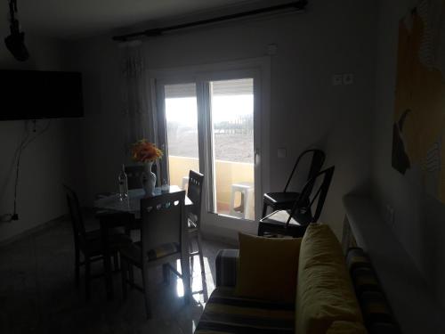 a living room with a table and a couch and a window at Montemar Studios & Apartments in Arkasa