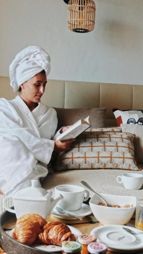 a woman reading a book in front of a table with food at Résidence & Hôtel Aria Marina in Propriano