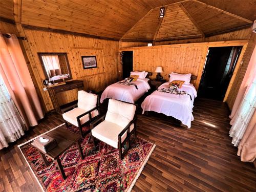a bedroom with two beds and chairs in a room at The Villas - Bedouin Boutique Resort in Wadi Rum
