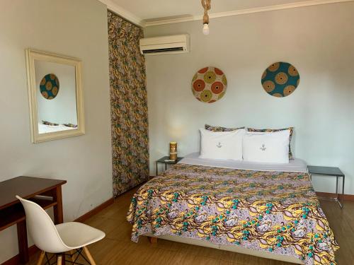 a bedroom with a bed and a desk and a chair at São Pedro Guesthouse in São Tomé
