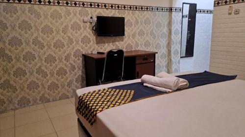 a bedroom with a bed and a desk and a tv at Bintang Khanida Syari'ah in Tjakranegara